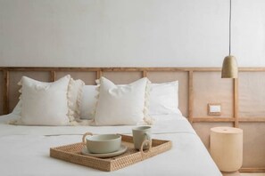 Relax in a serene space with a comfortable bed, a woven tray for morning refreshments, and a decorative vase.