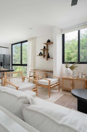 Relax in a serene space with a central seating area, shelf, and large windows offering a view of lush greenery.
