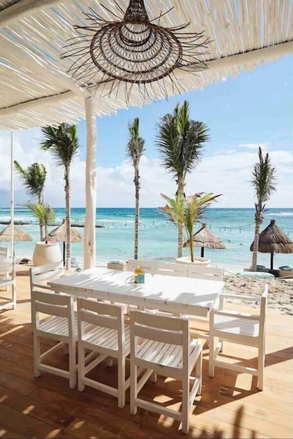 Enjoy meals under a thatched roof with ocean views surrounded by palm trees.