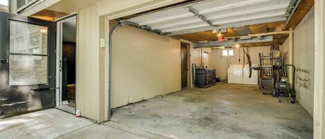 A garage with a concrete floor, a door leading to a vehicle, and a utility area with equipment.