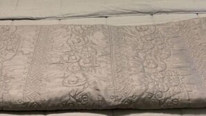 Ein Bett mit gemusterten Betttextilien und einem Kopfkissen mit dem Aufdruck "Hello, gorgeous!".