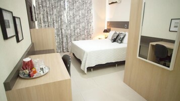 Una habitación de hotel con cama, mesita de noche y escritorio con silla.