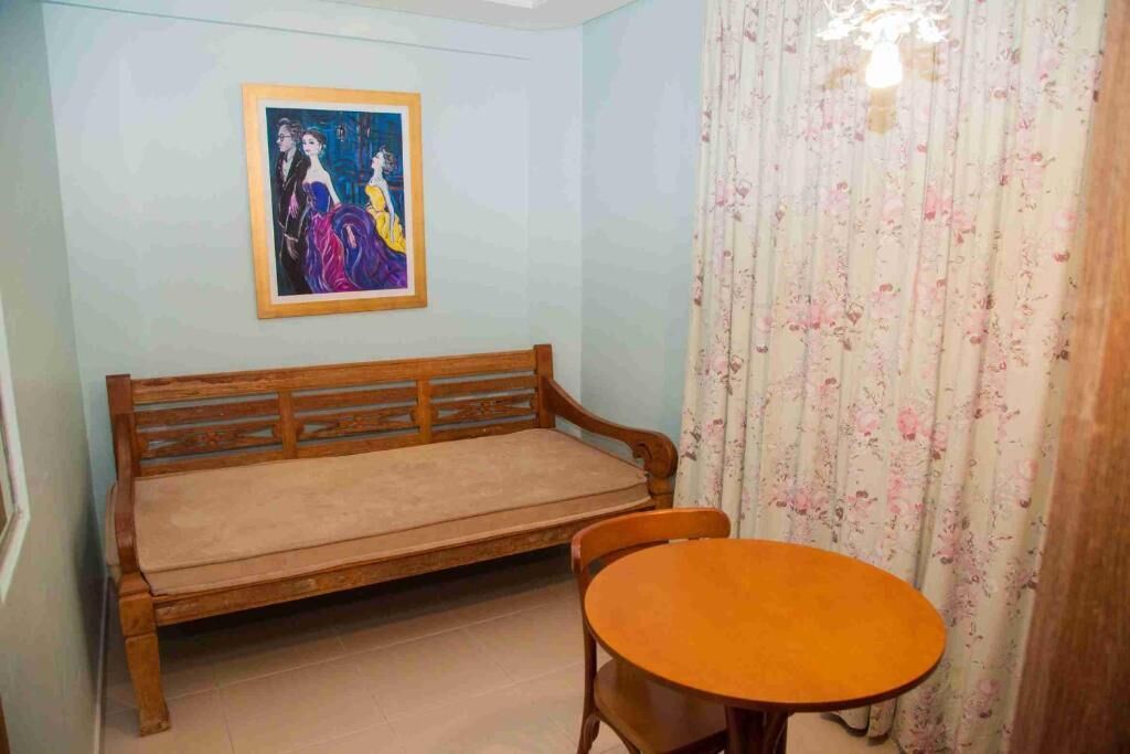 A room with a wooden bench, a round table, and a framed painting on the wall.