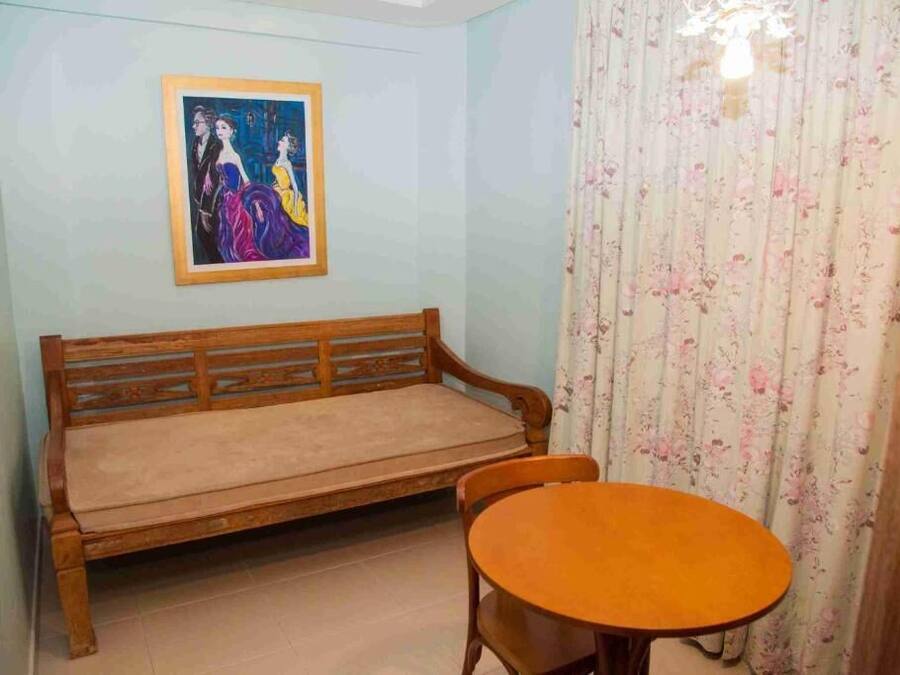 A room with a wooden bench, a round table, and a framed painting on the wall.