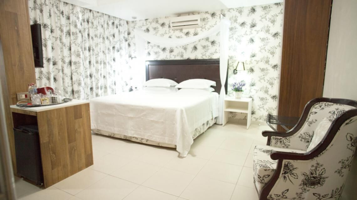 Une chambre d’hôtel comprenant un lit, une table de chevet, une chaise et un bureau avec une autre chaise.