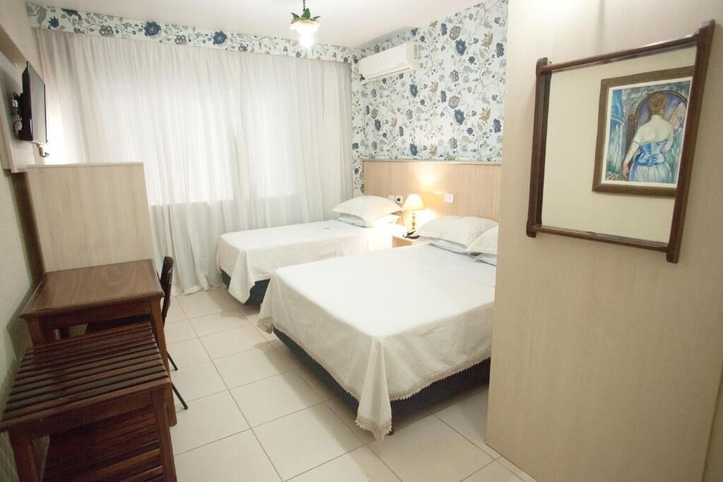 A hotel room with two beds, a desk, and a chair.