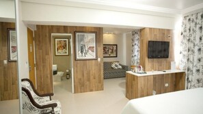 A hotel room with a bed, a wooden desk, a television, and framed artwork on the walls. - Hotel Royal Plaza (Apucarana)