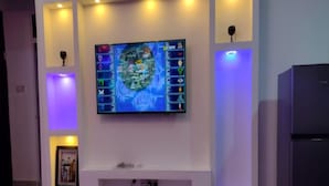 Een moderne woonkamer met een flatscreen televisie bevestigd aan een wit tv-meubel, omringd door inbouwverlichting.