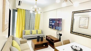 Un salon moderne comprenant un canapé, une table basse, une table à manger et un téléviseur à écran plat fixé au mur.