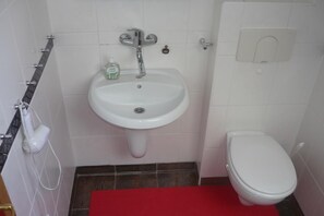 Un baño con un lavamanos blanco, un inodoro y una alfombra roja.