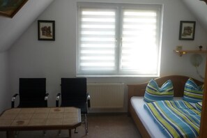 Una habitación con una cama, una mesa, dos sillas, un radiador y una ventana con persianas.