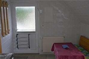 A small, compact room with a bed, a radiator, a window, and a door.