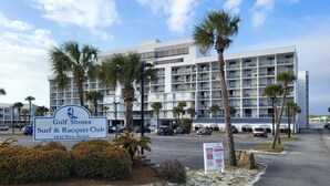 Un hotel con diversi balconi, palme e un cartello che indica essere il Gulf Shores Surf & Racquet Club al numero 1832 di West Beach.