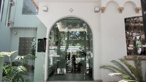 A building entrance with a glass door, surrounded by potted plants and a tiled roof. - Casa Lomah Napoles WTC (Mexico City)