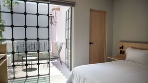 A bedroom with a bed, a wooden door, and a view of an outdoor patio with chairs and a table. - Casa Lomah Napoles WTC (Mexico City)