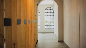 A corridor with wooden paneling, a tiled floor, and a large arched window with a view of greenery. - Casa Lomah Napoles WTC (Mexico City)
