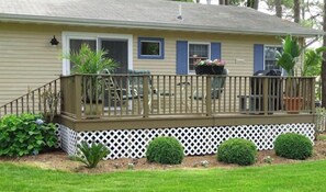 Une maison de plain-pied avec un porche couvert, une petite terrasse et une clôture blanche en bois.