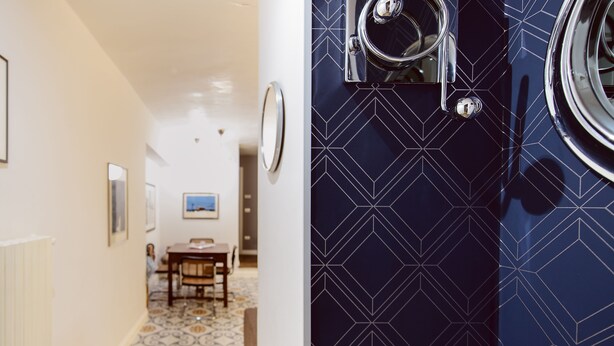 A hallway with patterned floor tiles, a dining area with a table and chairs, and a door with a geometric tile design. - Closed structure, not existing (Potenza)