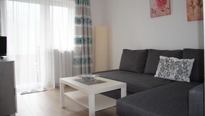 A modern living room with a grey sofa, a white coffee table, and a TV on a stand. - holiday apartment Serlesblick (Fulpmes)