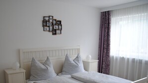 A double bed with a white headboard, two bedside tables, and a wall-mounted picture frame with various photos and text. - holiday apartment Serlesblick (Fulpmes)