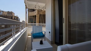 A balcony with a white chair, a small table, and a string of lights. - Lovely 3BR Apartment in Heart of Mohandseen (Giza Governorate)