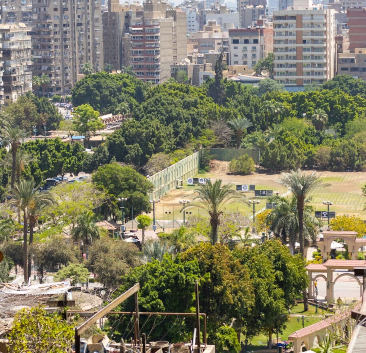 A high-rise urban area with dense residential buildings, a park with palm trees, and a sports field.