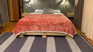 A bedroom with a wooden bed, a red quilt, two bedside lamps, and a grey textured rug. - SUEÑA@TierraAmada-in the heart of the valley 1OF7 (Guadalupe, Ensenada)