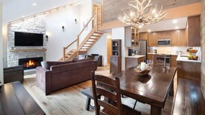 A spacious living area with a fireplace, a large wooden dining table, and a comfortable sofa.