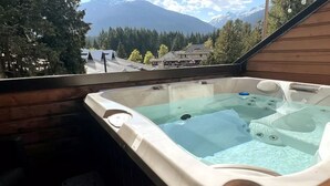 A hot tub with a view of mountains and houses.