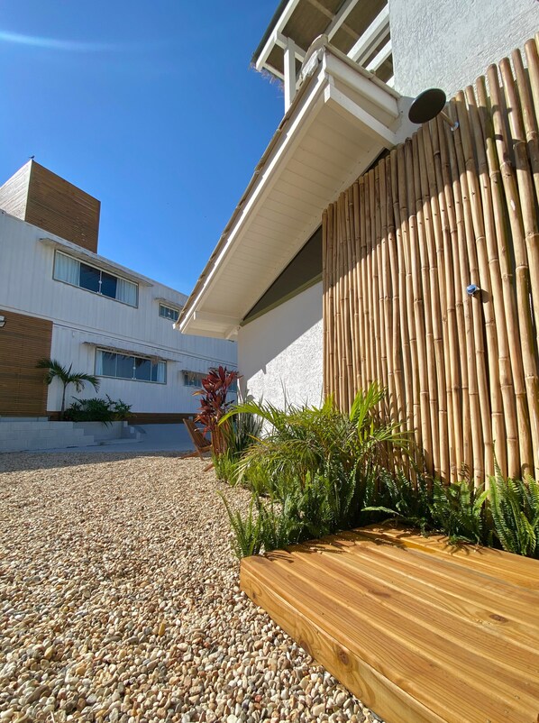 A modern building with a white exterior, a wooden deck, and a bamboo fence.
