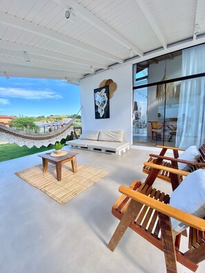 A spacious outdoor seating area with wooden furniture, a hammock, and a view of the landscape.