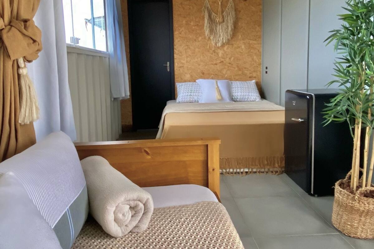 Une pièce comprenant un lit, un canapé, une petite table, une plante et un luminaire fixé au mur.