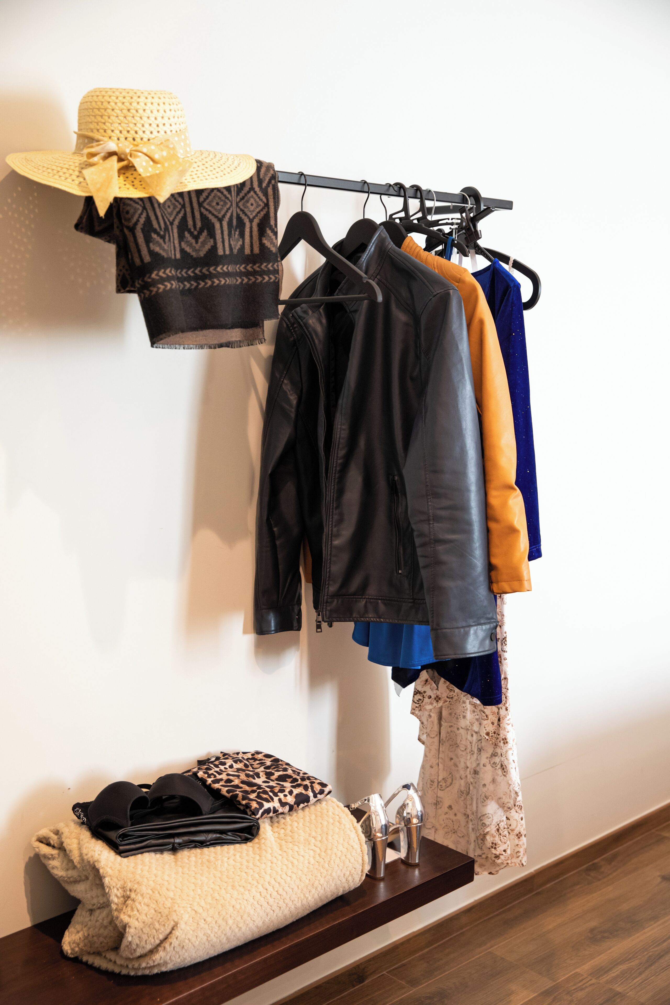 Un portant à vêtements avec différents articles, un chapeau et un sac plié contenant des accessoires, le tout posé sur une étagère.