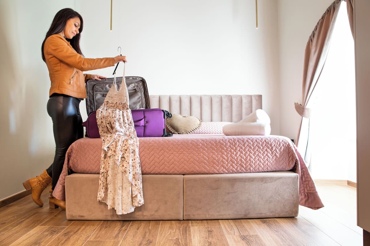 A room with a bed, a suitcase, and a hanging garment.