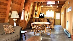 Interior acogedor de una cabaña de madera con un sofá, una mesa de comedor y sillas.
