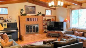 Interior acogedor de una cabaña con chimenea, televisor y muebles de madera.