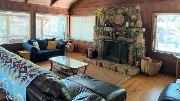 A cozy living room with a stone fireplace, wooden beams, and comfortable seating.