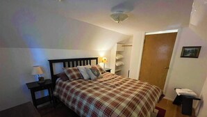 A bedroom with a bed, nightstands, a lamp, a wardrobe, and a door.
