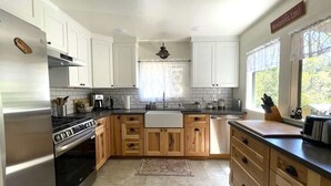 A modern kitchen with white cabinets, stainless steel appliances, and a large window providing natural light.