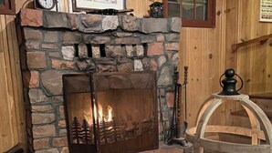A stone fireplace with a decorative panel, a wooden table, and a lantern.
