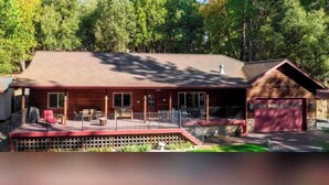 Une cabane en bois à deux étages, dotée d’un porche couvert et d’un garage.