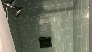 A bathroom with green tiled walls and a white bathtub.