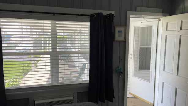 A bedroom with a bed, a window with blinds, a door, and a radiator.