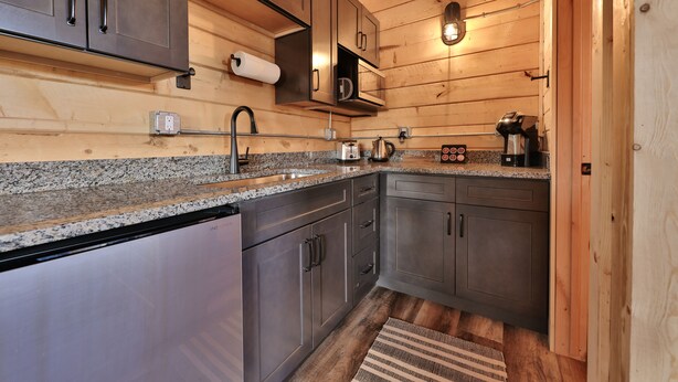 A compact kitchen with granite countertops, stainless steel appliances, and wooden cabinetry. - Muddy Creek Mining Company (Hanksville)