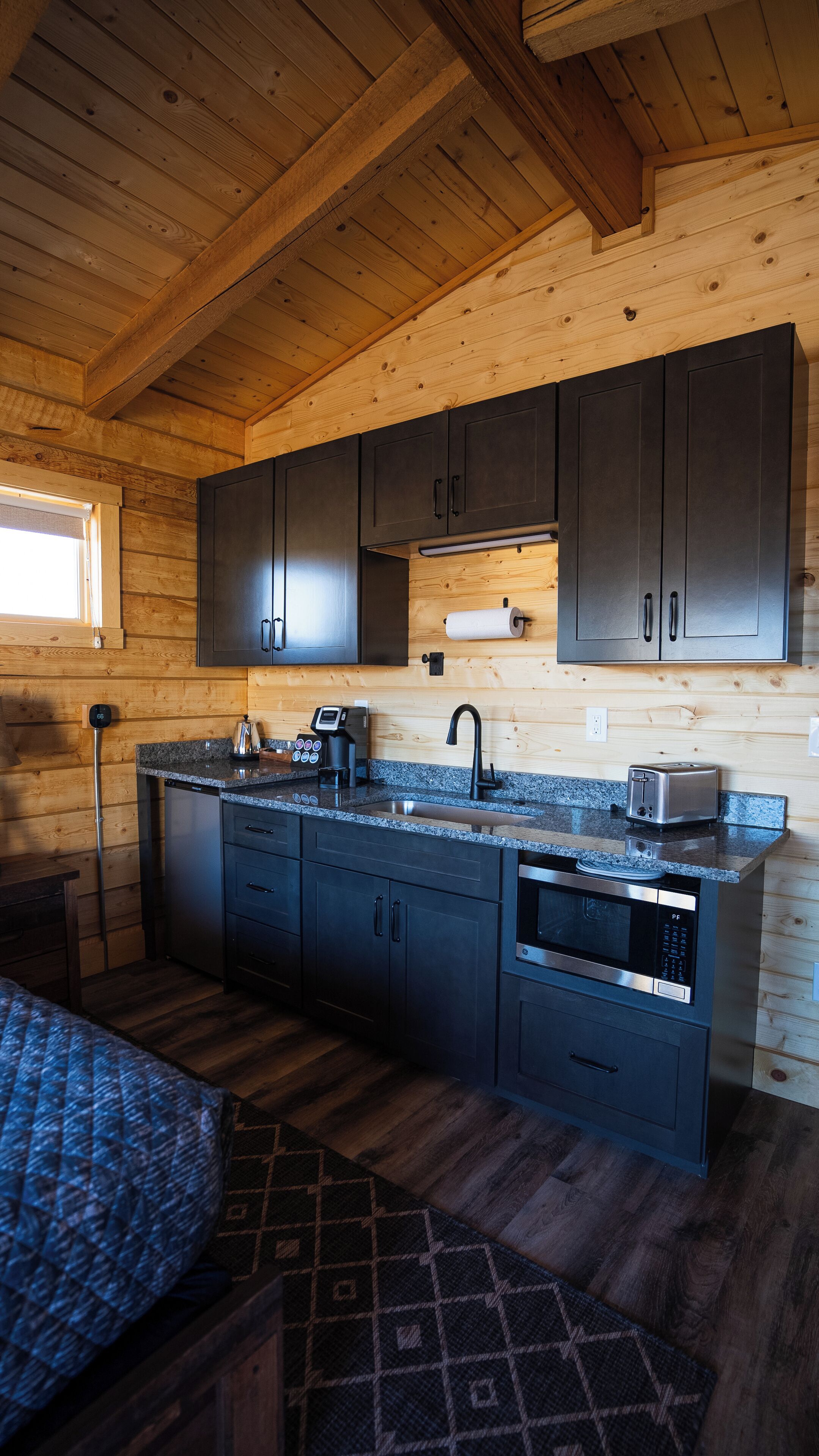 A compact kitchen with dark cabinets, a built-in microwave, and a coffee maker.