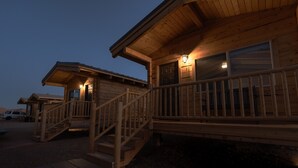 A wooden cabin with a porch, a staircase, and a vehicle in the background. - Muddy Creek Mining Company (Hanksville)