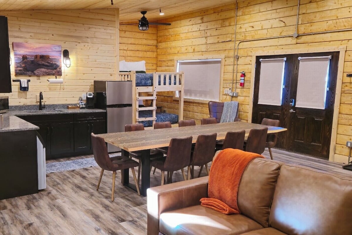 A cozy cabin interior with a wooden interior, a dining area, a kitchen, and a bathroom.