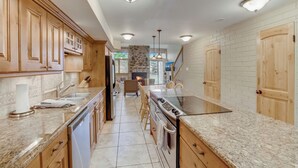 Una cocina con armarios de madera, encimera de granito, horno empotrado y una pared decorativa de piedra.