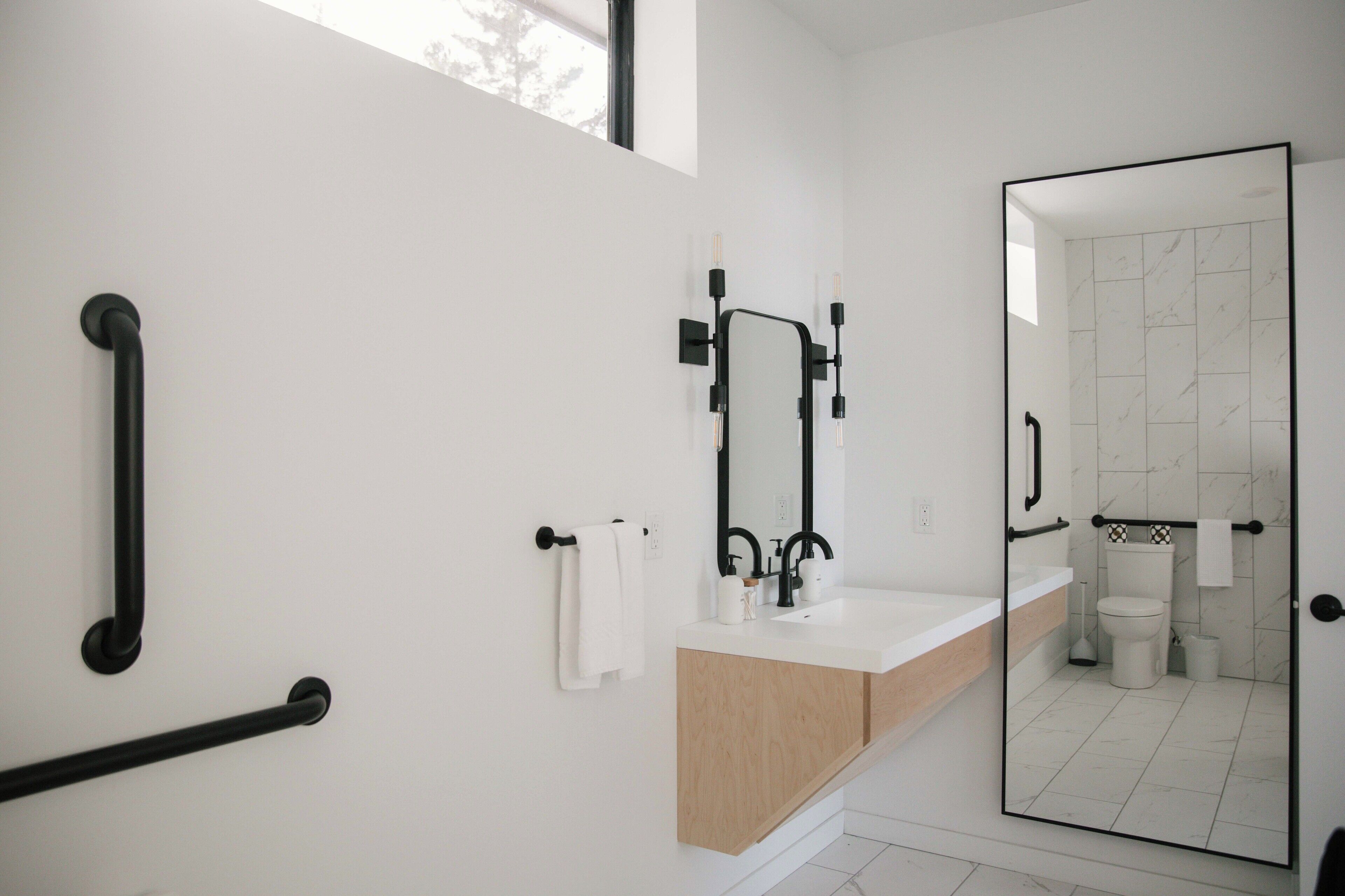 Un baño moderno con tocador blanco, grifería negra y cabina de ducha de vidrio.