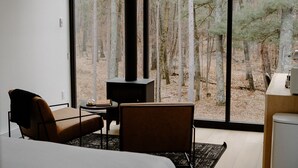 A modern bedroom with a large window, a fireplace, a bed, and a seating area. - Nature Link Resort (Nisswa)